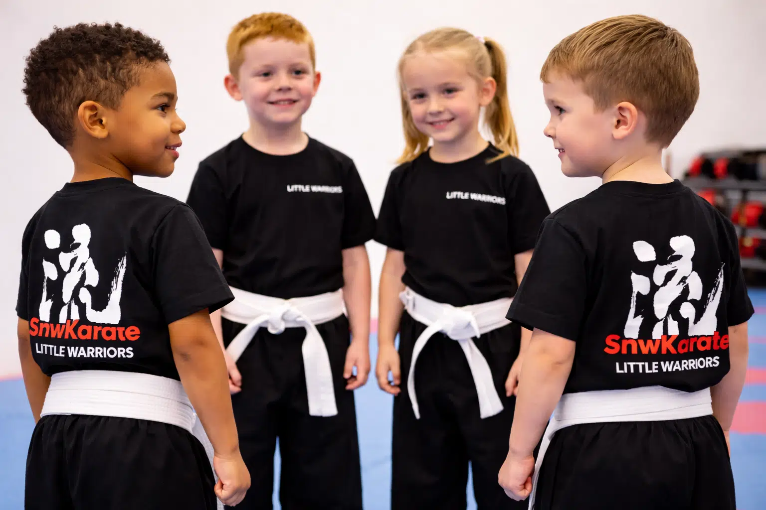 Four young children in Little Warriors SNW Karate uniform smiling during an early years martial arts class
