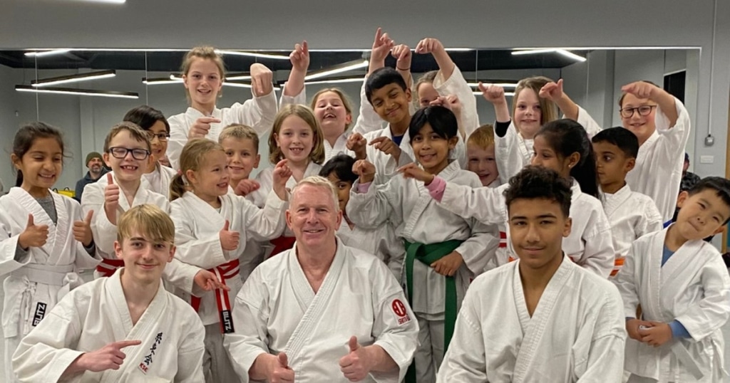 SNW Karate class in Chester — children and instructor smiling together in the dojo.